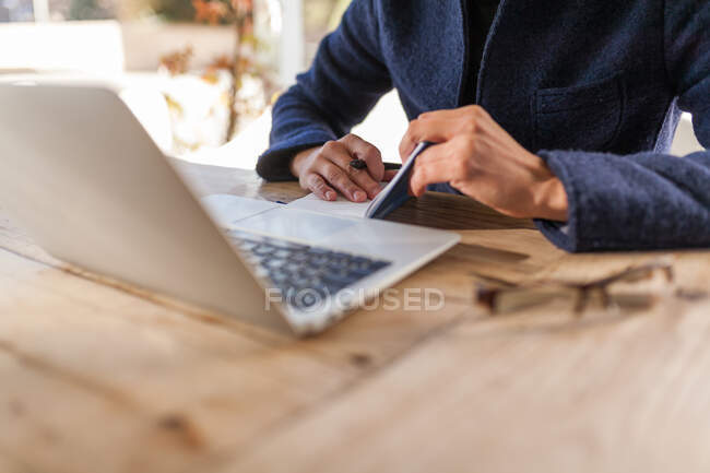 Crop Young male in trendy outfit browsing netbook while working on project on street — Stock Photo