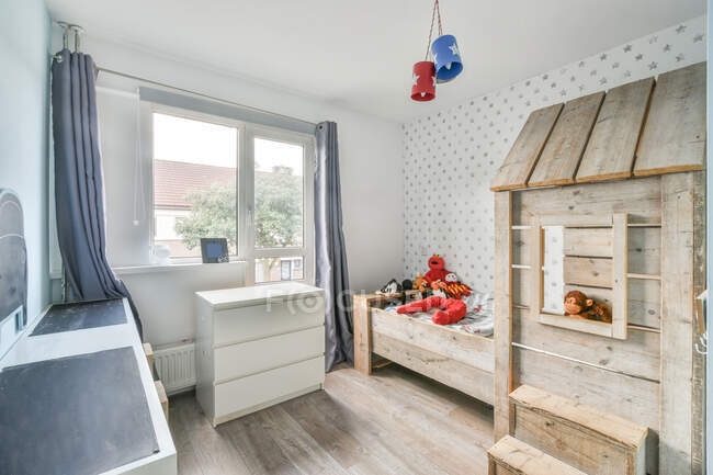 Сучасний інтер'єр просторої затишної дитячої з дерев'яним ліжком і комодом в сучасному котеджі — стокове фото
