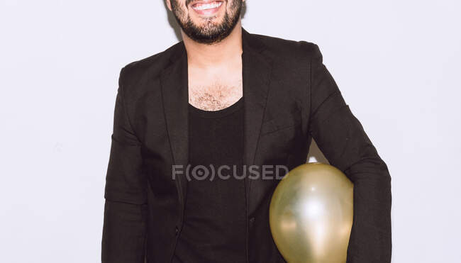 Joyful crop unrecognizable bearded man with balloon laughing with mouth opened against white background during party — Stock Photo