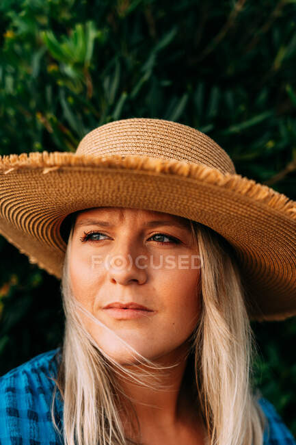 Wistful adult female tourist in hat looking away against bush in Saint Jean de Luz France — Stock Photo