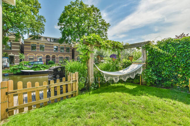 Terrasse de la maison résidentielle avec des plantes vertes et hamac sous le ciel bleu dans la journée ensoleillée — Photo de stock