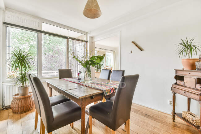 Interior da acolhedora sala de jantar com mesa de madeira e cadeiras de couro macio em casa de campo projetado em estilo rústico — Fotografia de Stock