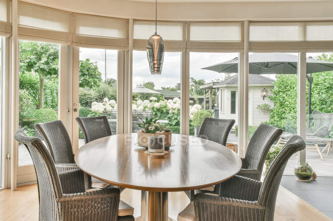 Design creativo della sala da pranzo e della cucina con poltrone e tavolo sotto le lampade appese alla parete della finestra a casa — Foto stock