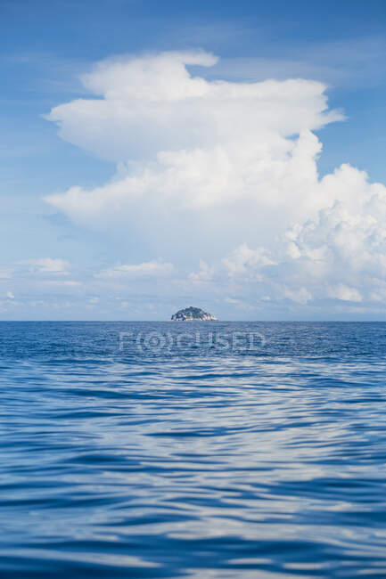 Сцени ясного блакитного хвилястого моря з скелястим островом на горизонті під хмарами в сонячний день в Малайзії — стокове фото