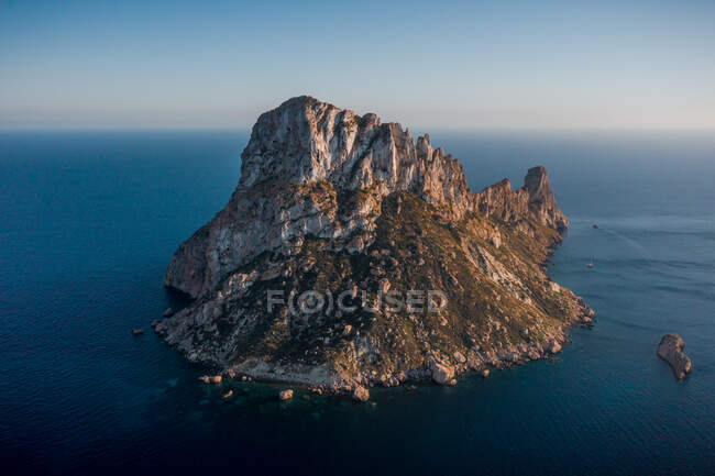 Drone vista della formazione rocciosa in mare increspato sotto il cielo chiaro al crepuscolo in Ibiza Spagna — Foto stock