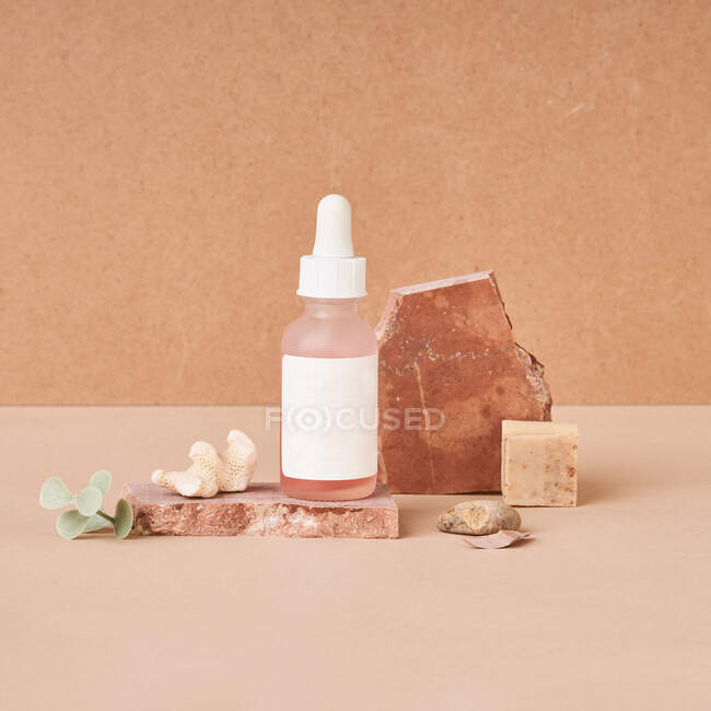 Pequena garrafa de óleo de beleza e peças de sabão artesanais naturais com pedra-pomes em fundo de duas cores — Fotografia de Stock