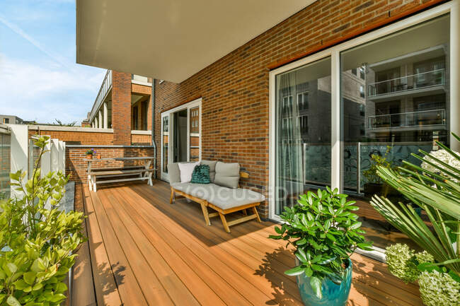 Couch und Tisch auf der Veranda des Wohnhauses mit Topfpflanzen in der Nähe von Glastüren — Stockfoto