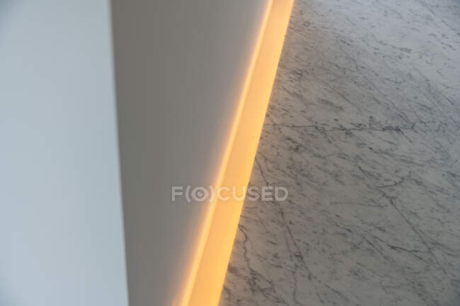 De cima da iluminação amarela colocada ao longo da parede branca no quarto no apartamento — Fotografia de Stock