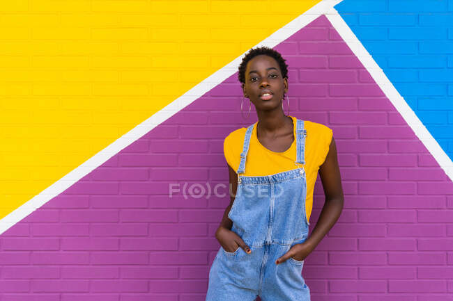 Jeune femme afro-américaine debout sur un mur lumineux coloré — Photo de stock