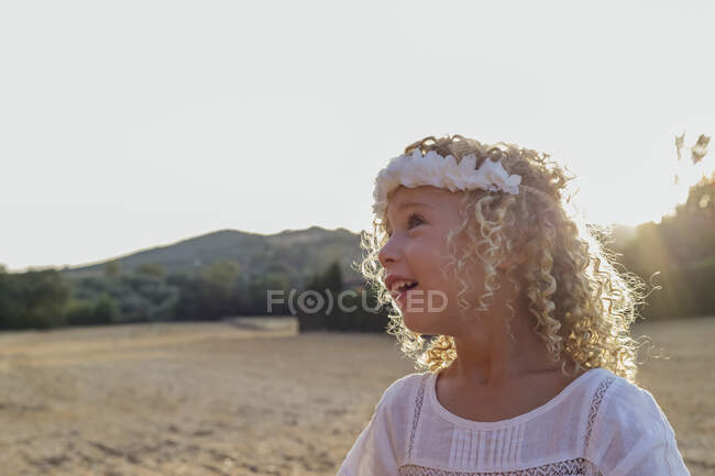 Vista lateral niña rubia solo en un campo en un día soleado - foto de stock