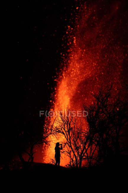 Silueta humana de pie contra la explosión de lava y magma saliendo del cráter. Cumbre Vieja erupción volcánica en La Palma Islas Canarias, España, 2021 - foto de stock