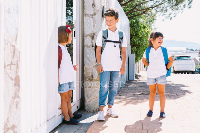 Freundliche Schulkinder in lässiger Kleidung sprechen, während sie an sonnigen Tagen Zeit auf dem gefliesten Gehweg verbringen — Stockfoto