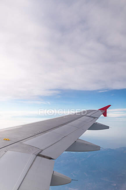 Attraverso la finestra del velivolo vista di soffici nuvole sopra il mare e il terreno durante il viaggio durante il giorno — Foto stock