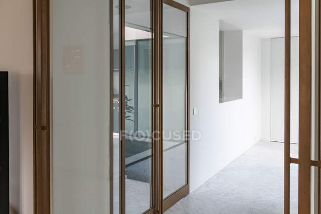 Portes coulissantes en verre dans un couloir spacieux avec murs blancs et sol en marbre dans une maison moderne à la lumière du jour — Photo de stock