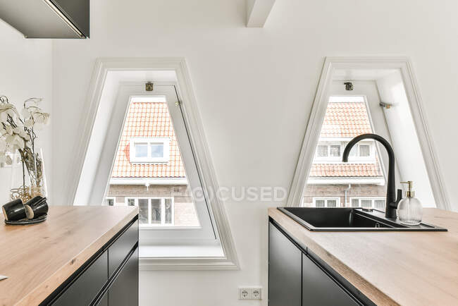 Cozinha moderna com pia curva preta e torneira com janelas triangulares no fundo — Fotografia de Stock