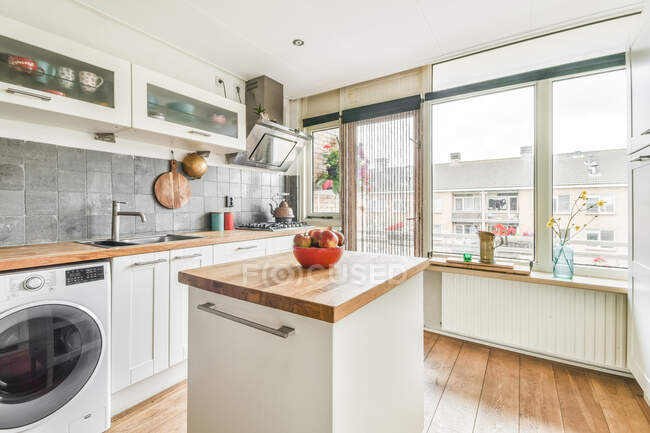 Інтер'єр просторої кухні з сучасною технікою і білими меблями в квартирі, спроектованій в мінімальному стилі — стокове фото