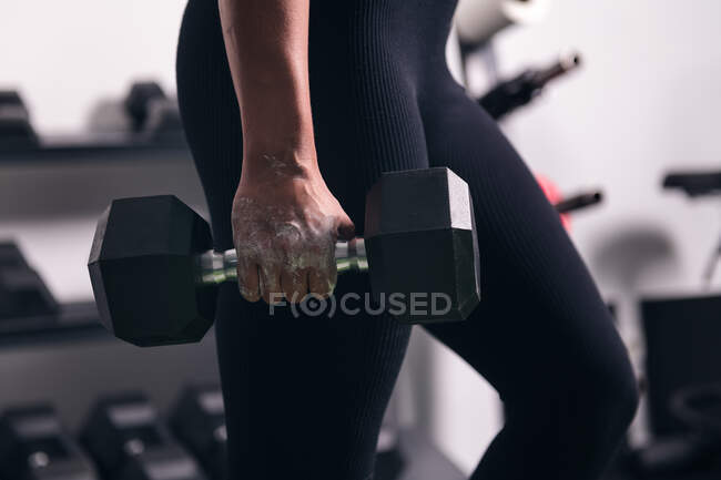 Crop strong sportswoman doing exercise with dumbbell during workout in gym — Stock Photo