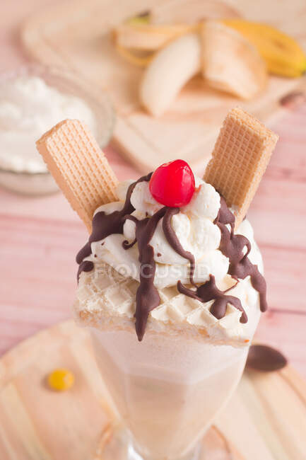 Milkshake sucré appétissant décoré de crème fouettée et gaufres et cerise sur le dessus — Photo de stock