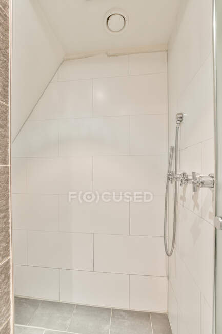 Cabina de ducha vacía con puerta de cristal abierta y paredes de baldosas blancas en baño ligero en apartamento - foto de stock