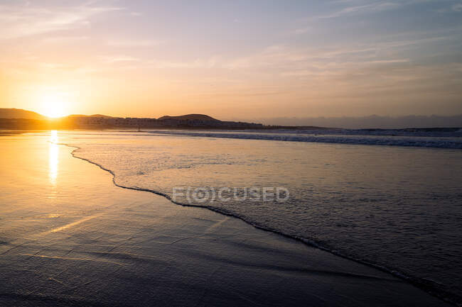 Malerischer Blick auf welliges Meer und Strand von Famara gegen Berge bei Sonnenuntergang in Teguise Lanzarote Kanarische Inseln Spanien — Stockfoto