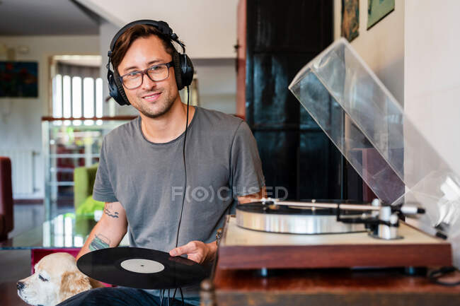 Homme concentré dans les lunettes écouter de la musique dans les écouteurs du lecteur dans un appartement spacieux — Photo de stock