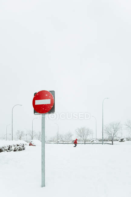Señal de tráfico roja que prohíbe la entrada en poste en nieve cerca de la carretera en el día de invierno en Madrid - foto de stock