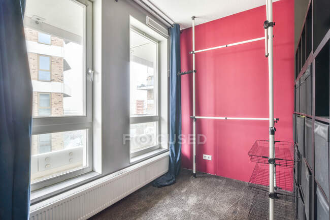 Interno di moderno armadio luminoso con parete rosa e tende blu e funzionale organizzatore sistema di stoccaggio e appendini — Foto stock