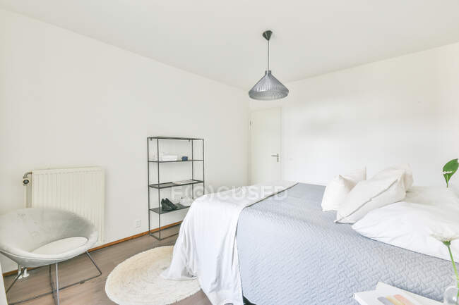 Interno di camera da letto contemporanea con letto morbido e comodino in legno progettato in stile minimale in piano — Foto stock