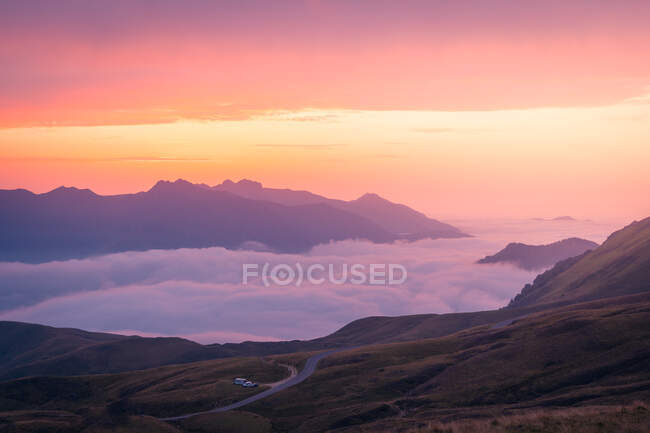 Dichter weißer Nebel schwebt am Sommerabend in der wilden Natur Spaniens in der Nähe des rauen felsigen Bergrückens vor bewölktem Himmel — Stockfoto