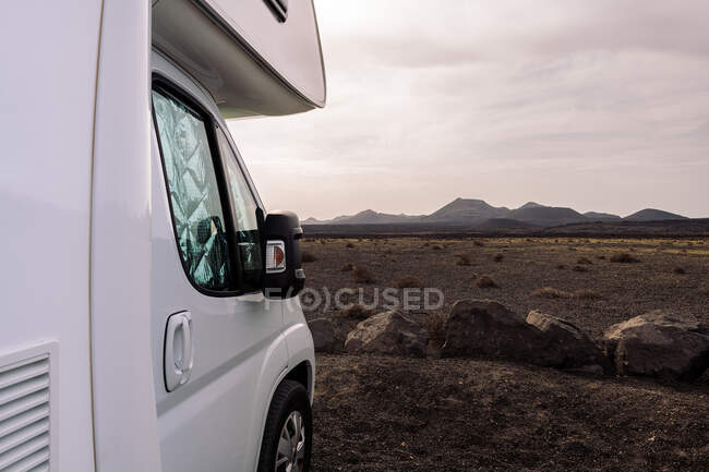 Scenic view of vehicle parked against volcano Cuervo and mountains under cloudy sky in Tinajo Lanzarote Canary Islands Spain — Stock Photo
