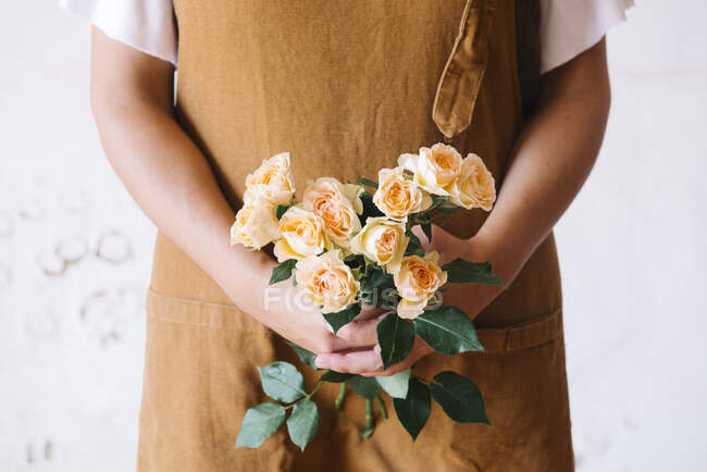 Anonimo adulto ispanico fiorista femminile in grembiule disporre bouquet di fiori freschi delicati assortiti sullo sfondo bianco — Foto stock