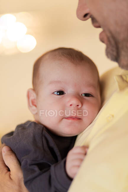 Cultiver père méconnaissable embrassant adorable nouveau-né regardant la caméra en plein jour — Photo de stock