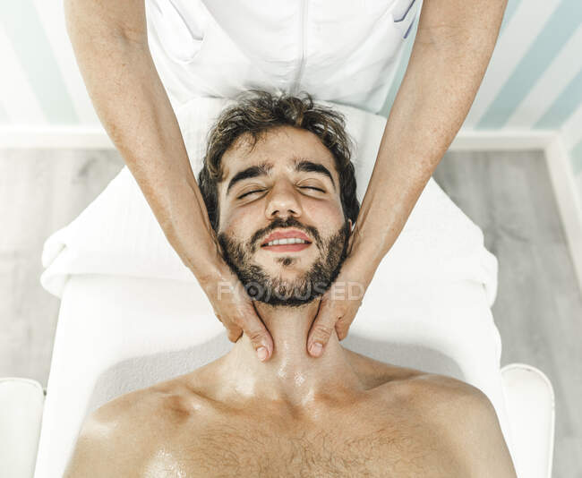 Top view of guy closing eyes while having neck massaged by crop anonymous master — Stock Photo