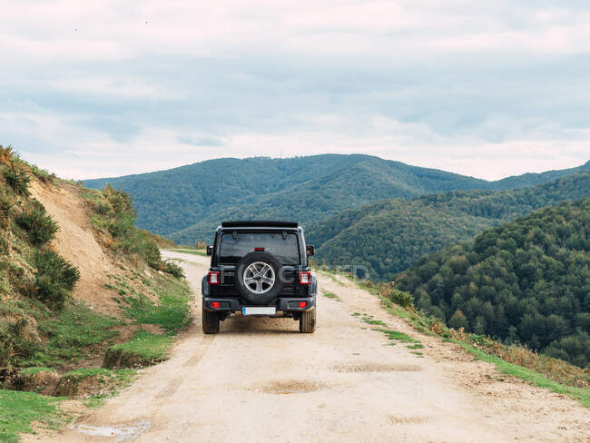 Вид на внедорожник, проезжающий по грубой дороге во время путешествия в живописной горной долине — стоковое фото
