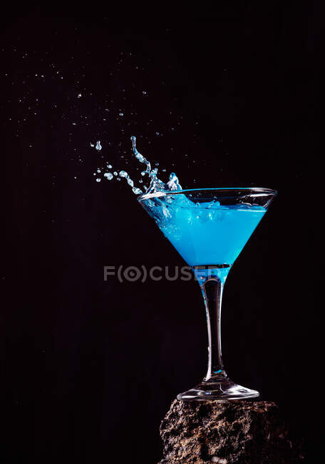 Cocktail Blue Lagoon en cristal élégant placé sur une surface rugueuse sur fond noir — Photo de stock