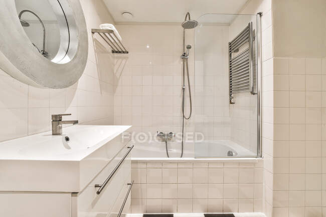 Keramik-Waschbecken unter Spiegel gegen Dusche und Badewanne im modernen Badezimmer mit gefliester Wand im Haus — Stockfoto