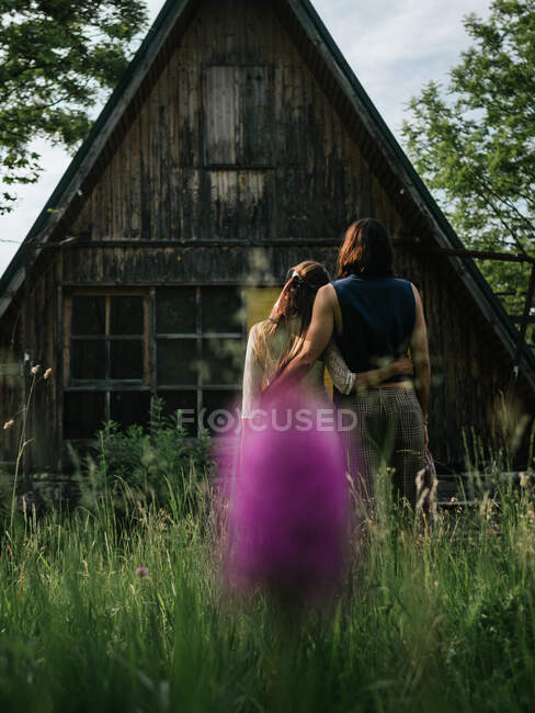 Vista posteriore di coppia attraente che si abbraccia di fronte a una vecchia casa di legno dall'alto — Foto stock