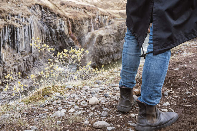 Crop viajante irreconhecível em roupas casuais de pé em solo rochoso áspero no topo do desfiladeiro Studlagil na Islândia durante o dia — Fotografia de Stock