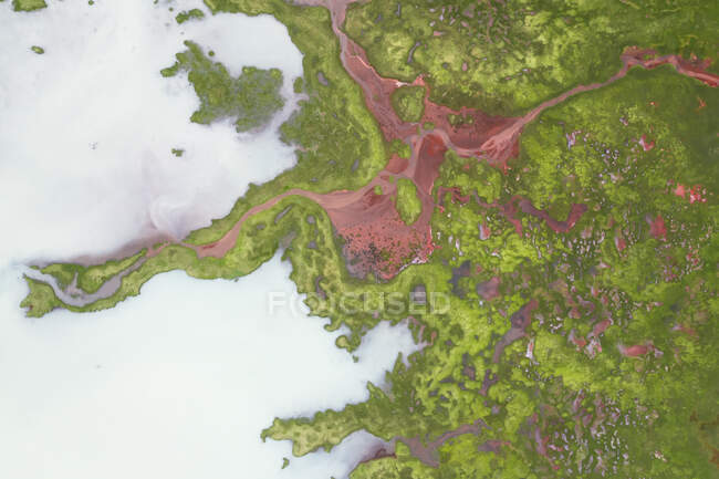Drone vista de formações marrons rochosas ásperas cercadas por plantas verdes exuberantes cobertas com névoa grossa na natureza da Islândia — Fotografia de Stock
