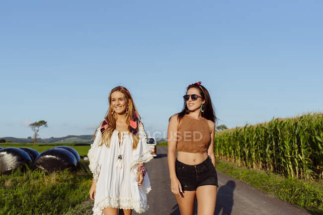 Duas amigas felizes vestidas com roupas de verão se divertindo fora de uma van vintage em um dia ensolarado — Fotografia de Stock
