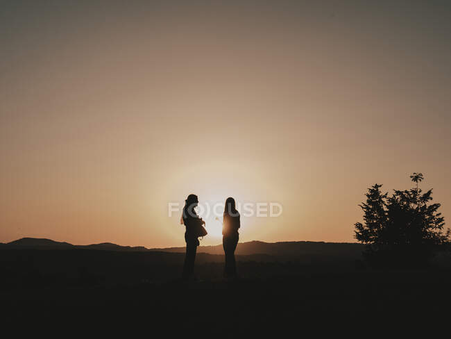 Silhouetten eines Paares in der Natur, während sich die Sonne in den Bergen versteckt — Stockfoto
