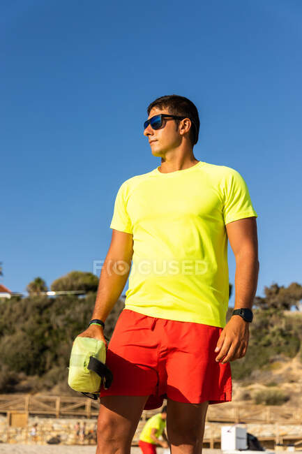 Man lifeguard in shorts and t shirt and maintaining safety on sandy seashore — Stock Photo