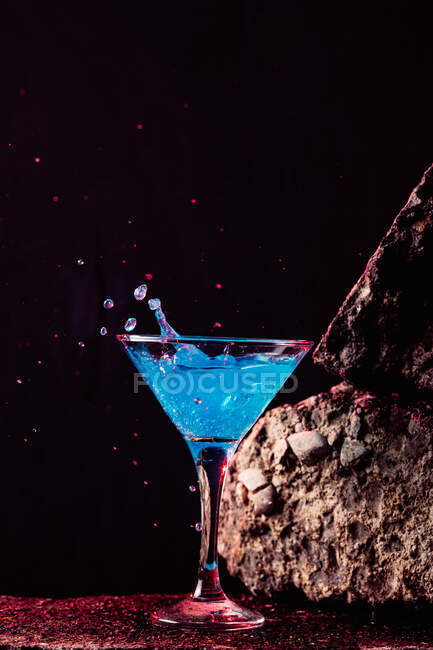 Синій коктейль лагуни в кристалі елегантного скла розміщений на грубій поверхні на чорному тлі. — стокове фото