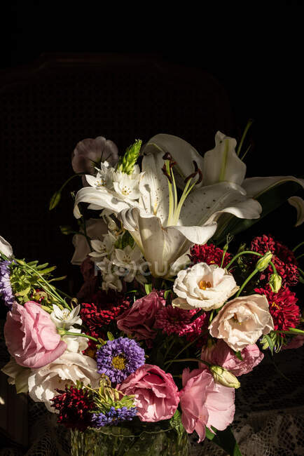Bouquet di fiori freschi tra cui gigli bianchi eustoma e aster in vaso di vetro al sole — Foto stock