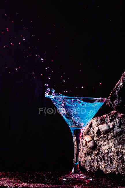 Blue Lagoon Cocktail in Kristall elegantes Glas auf rauer Oberfläche vor schwarzem Hintergrund platziert — Stockfoto