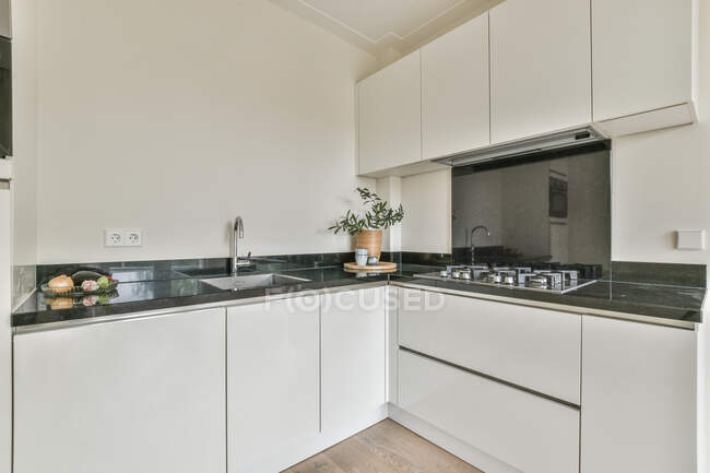 Interno della cucina luminosa con mobili in stile minimalista bianco ed elettrodomestici in appartamento contemporaneo — Foto stock