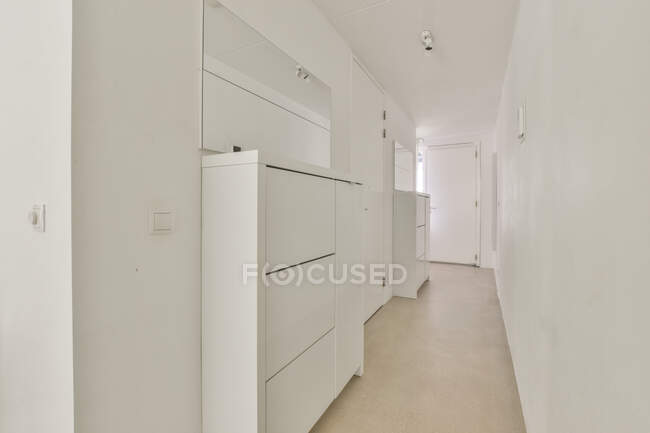 Estreito corredor interior com armários brancos e espelhos em forma retangular contra a parede em casa de luz — Fotografia de Stock