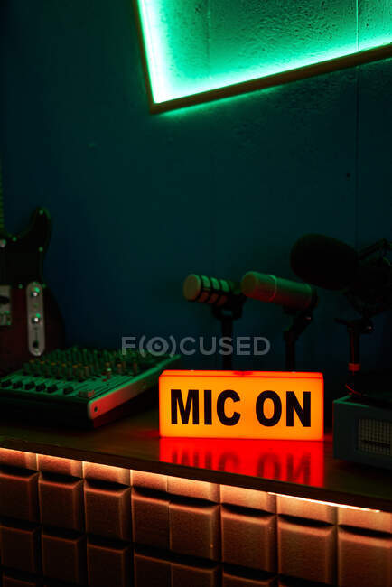 Modern microphones on tripod placed on table in dark studio with neon illumination before recording podcast — Stock Photo