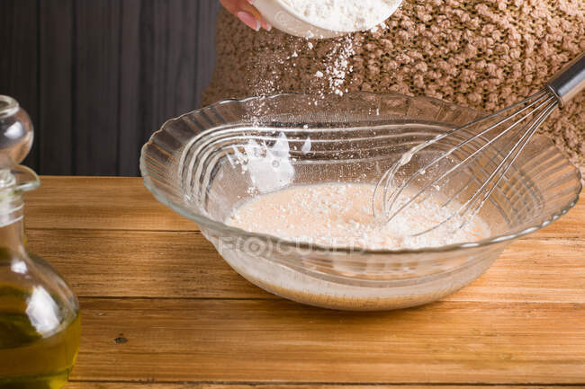 Cultive farinha feminina anônima derramando em tigela com leite e ovo enquanto prepara a massa de crepe na mesa de madeira na cozinha — Fotografia de Stock