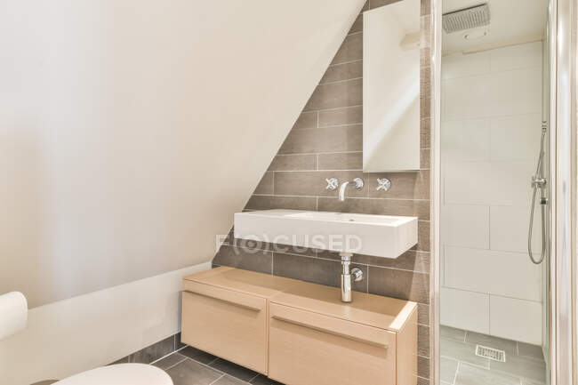 Interior de baño ligero con lavabo blanco y cabina de ducha en apartamento moderno - foto de stock